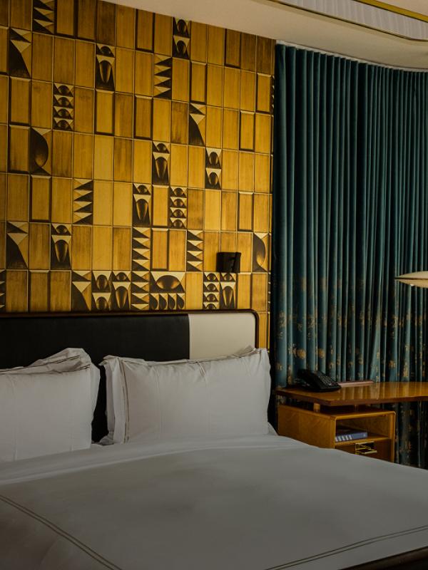 A chique hotel room with a patterned yellow accent wall at Viceroy Chicago