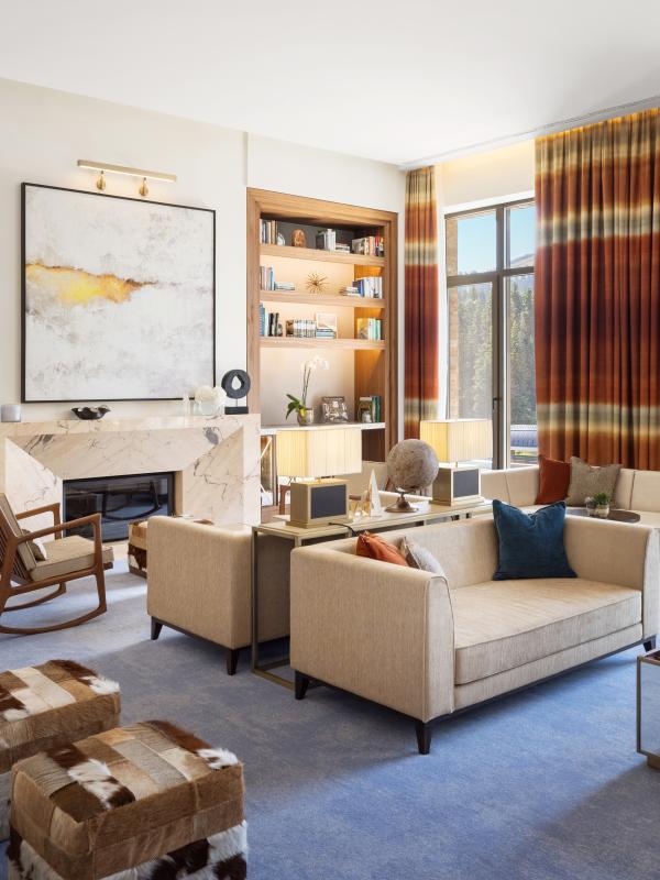 The Library, an airy lounge at Viceroy Kopaonik Serbia, with ample comfortable seating and several wall-to-ceiling bookshelves and a view of the mountain
