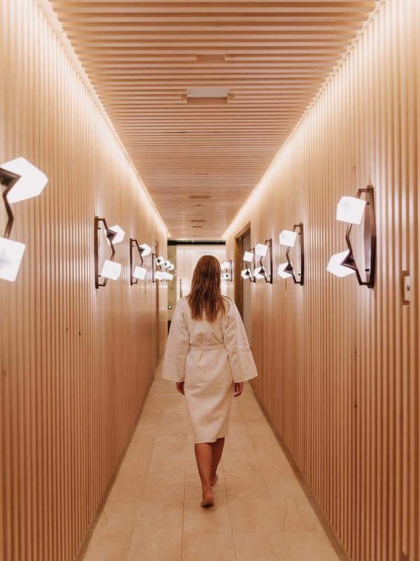A woman in a bath robe walks along a wood-panelled corridor at the Viceroy Kopaonik Serbia spa