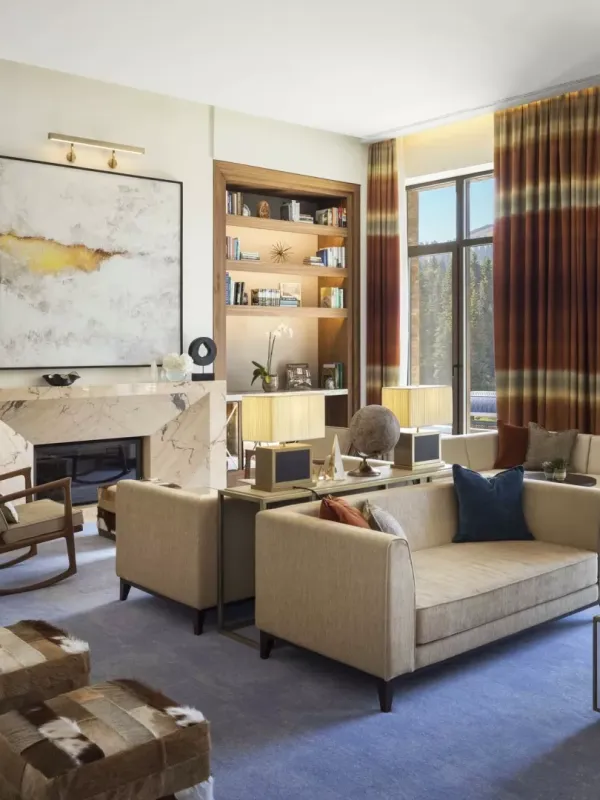 The Library, an airy lounge at Viceroy Kopaonik Serbia, with ample comfortable seating and several wall-to-ceiling bookshelves and a view of the mountain