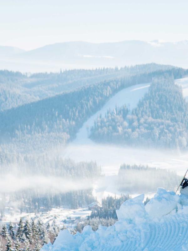 Two snowboarders on a ridge look out at the Kopaonik mountain range