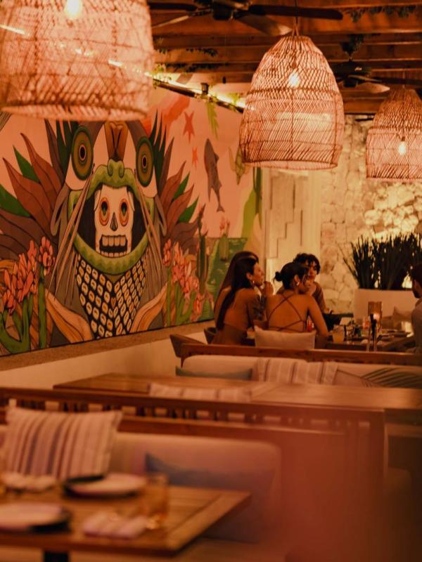 Diners eat in a booth at Awacate, next to a large mural