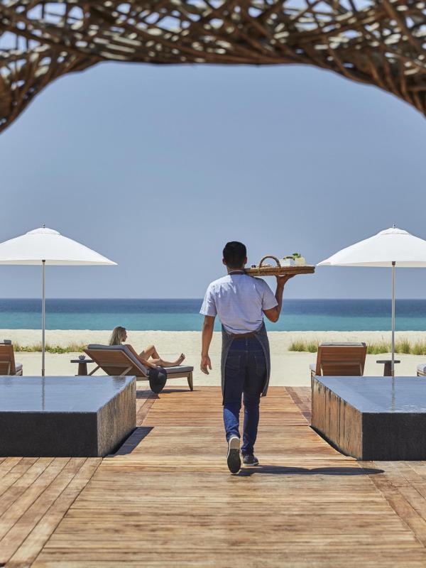 A server brings drinks to the beach-side bar Nidito, a paddock adjacent to Nido restaurant