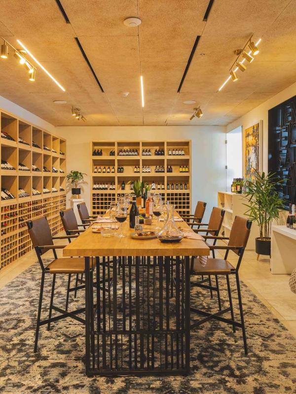 Viceroy Los Cabos' Wine Room, a bright cellar with floor-to-ceiling wine racks, surrounding a large dining table