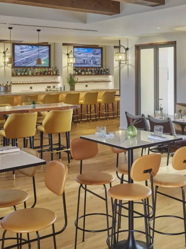 The Casa e Fora dining room at Ombria Algarve, with high four-top tables and a long bar section with wall-mounted televisions