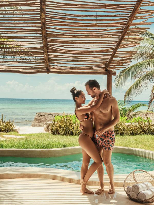 A couple in swimwear holding each other by their private pool at Viceroy Riviera Maya