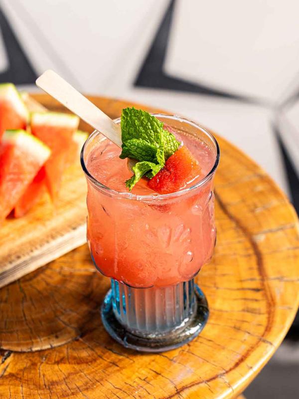 A melon-based cocktail on a table with chopped watermelon