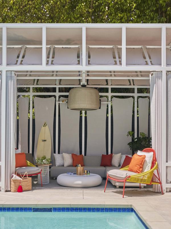 A cabana with a long couch and lounger chairs near the pool at Viceroy Santa Monica