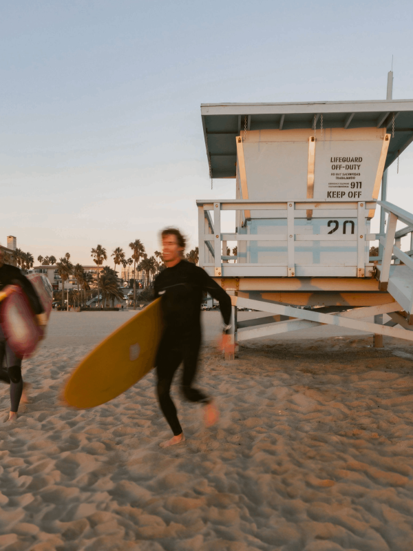 2 men running with surfboards on the beach at Viceroy Santa Monica