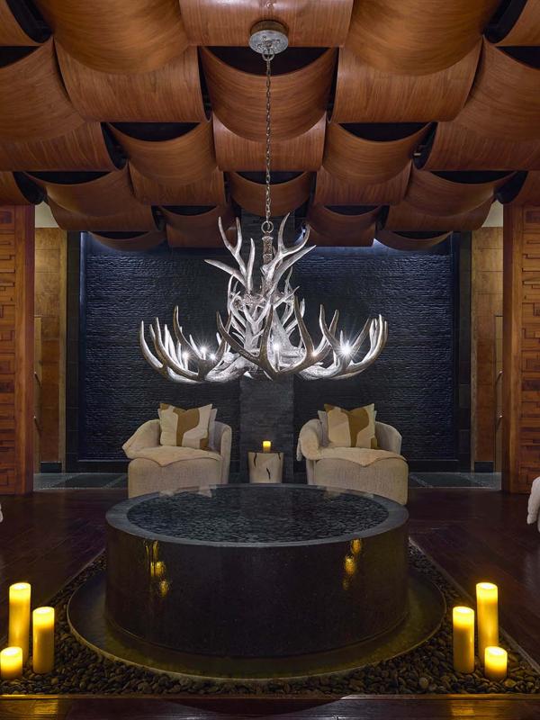 A dime lit spa room with large round loungers and candles lit along the floor at Viceroy Snowmass