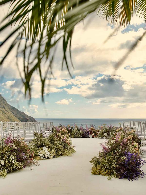 A beach front wedding set up with rows of seats against a sunset