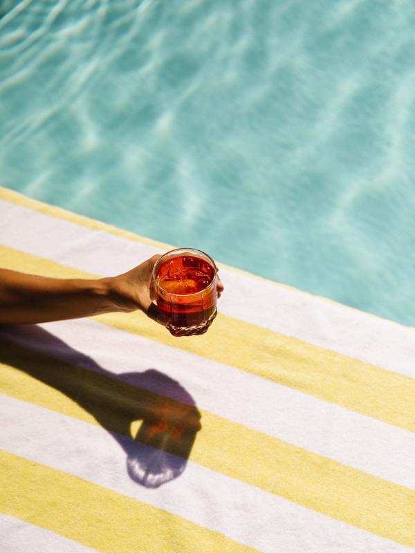 A hand holding a cocktail at a pool