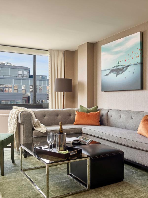 A room at Viceroy Washington DC with an L-shape couch, coffee table, chair, and balcony