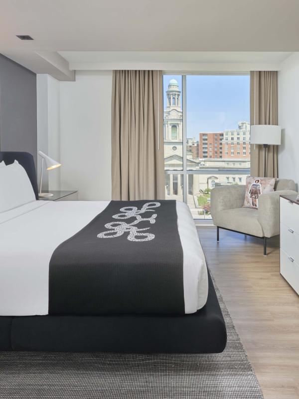 A king bed, dresser, TV, chair, and balcony in a room at Viceroy Zena Washington DC