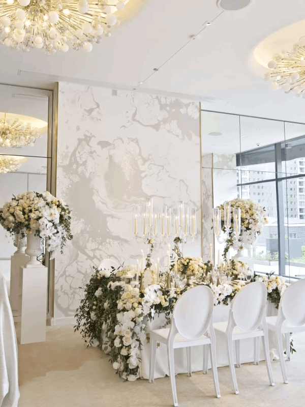 A room with a table with 3 chairs setup with wedding decorations and a table off to the left side with a wedding cake on it at a venue at Viceroy Chicago
