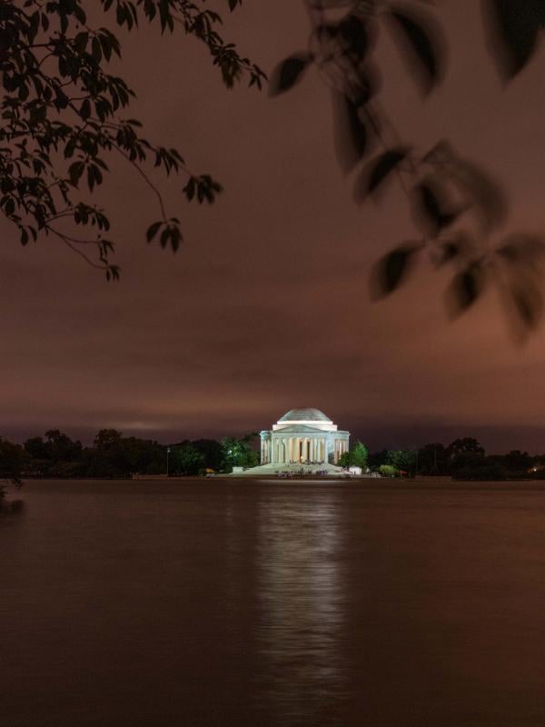 washington monument lit up at night from across a body of water