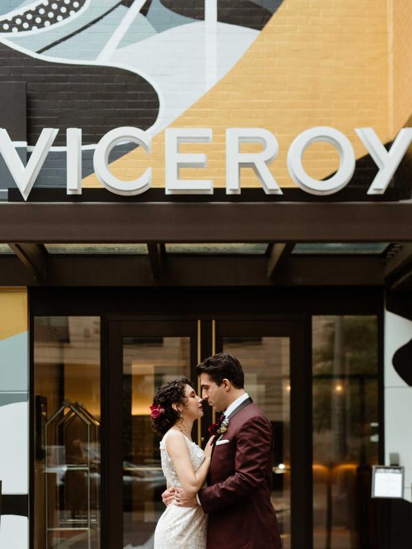 couple stand in front of colourful hotel with Viceroy sign