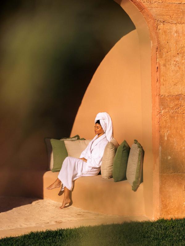 A woman sits in the sun outside of a spa