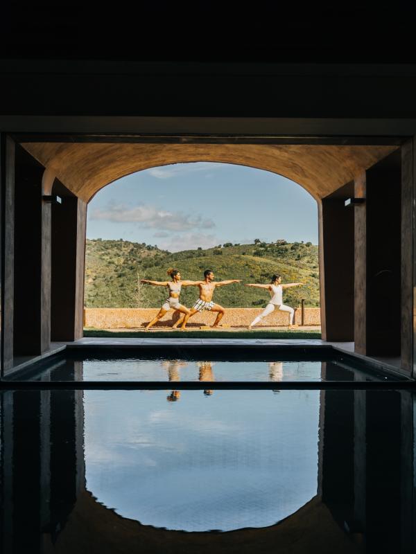 group of people doing yoga pose in background with water in foreground