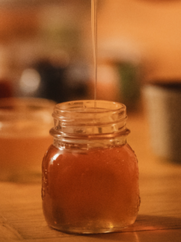 Honey being drizzled into a glass jar