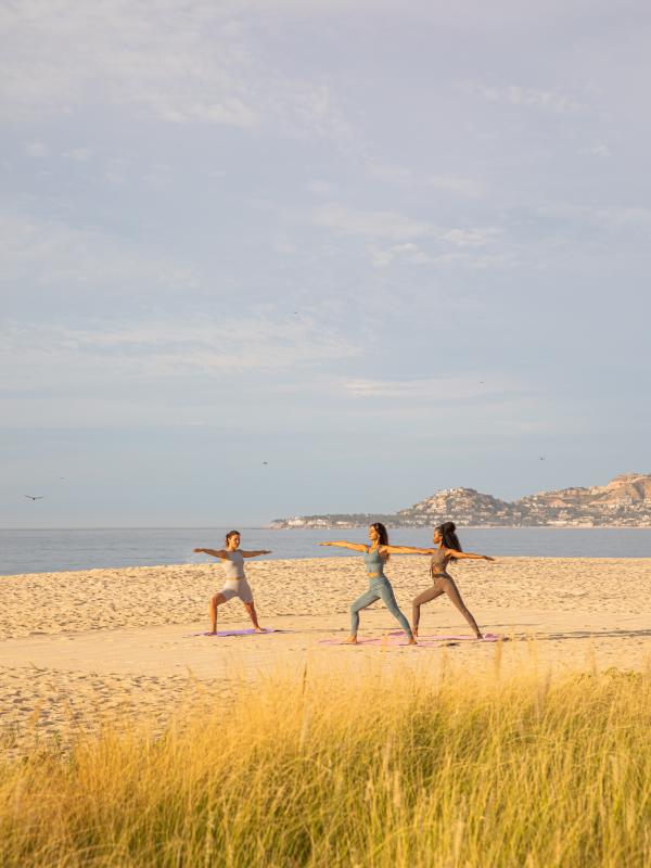 three people in yoga pose on beach