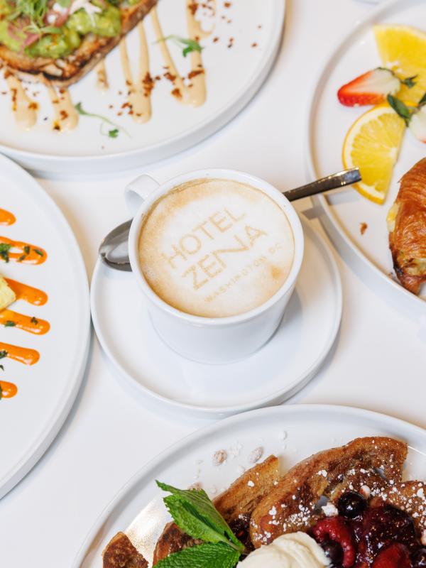 Brunch items from Figleaf, arranged on a table: Vanilla French Toast, Omelette, Avocado Toast, Croissant sandwich, and a latte.