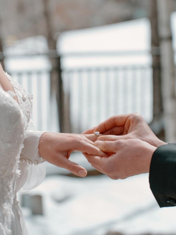 A groom putting on a ring on the brides finger