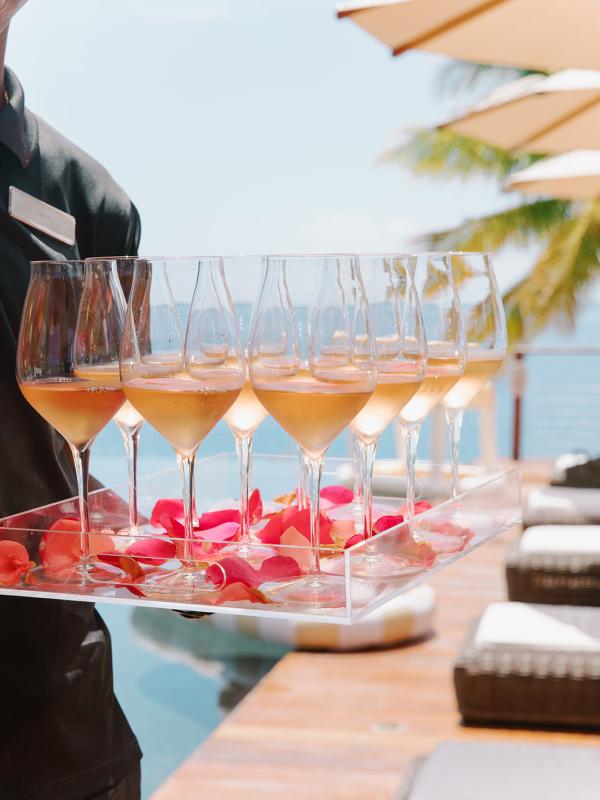 Des verres à vin disposés sur un plateau parsemé de pétales de fleurs
