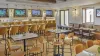 The Casa e Fora dining room at Ombria Algarve, with high four-top tables and a long bar section with wall-mounted televisions