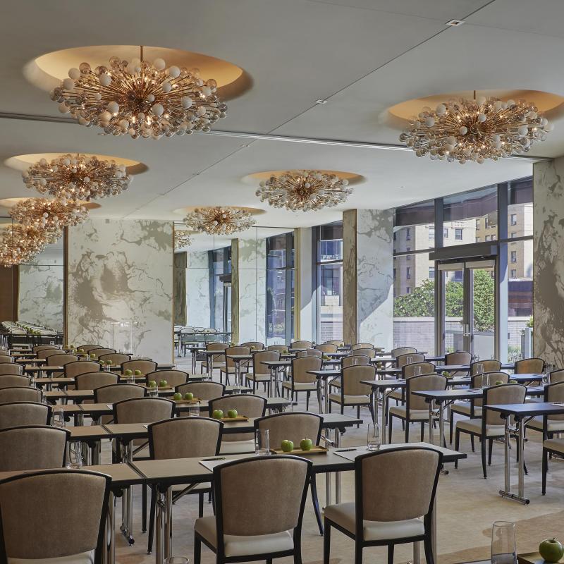 A long meeting room with rows of desk under a set of ornate pendant lights at Viceroy Chicago