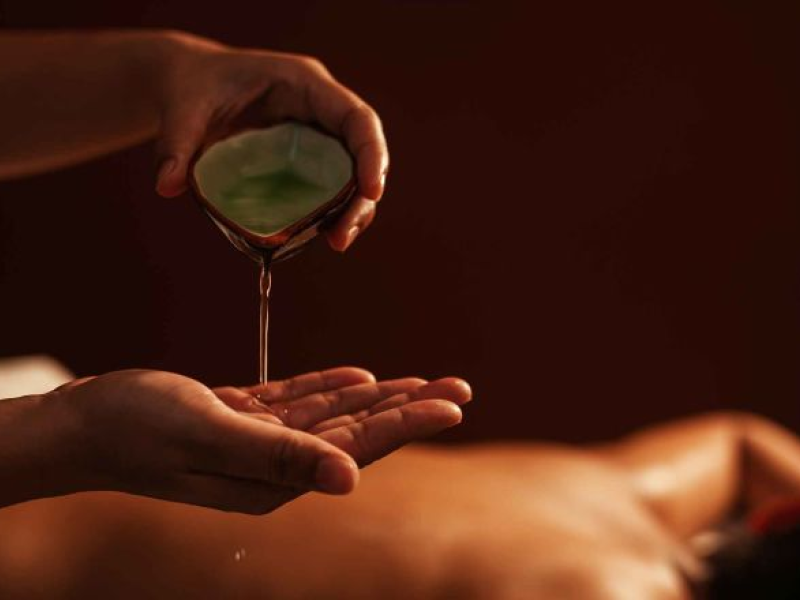 A masseuse pours oil on their hands.