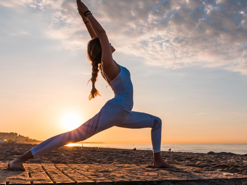Uma mulher pratica ioga na Santa Monica ao pôr do sol