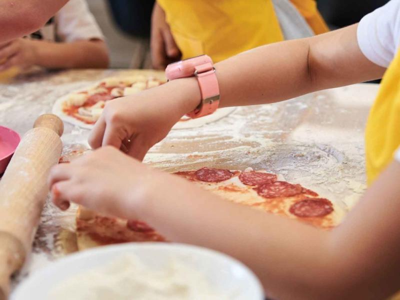 Kids putting ingredients on personal pizzas