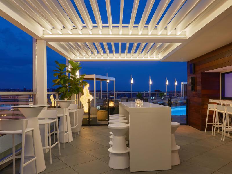 Hedy's Rooftop, a chic patio with heat lamps and a white lattice canopy, at night