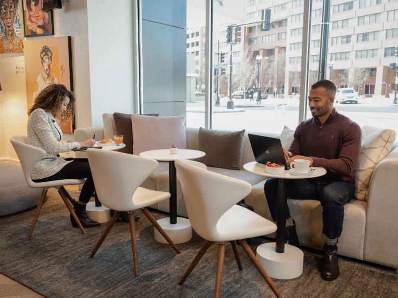 Two people working at individual tables at a workspace at Zena Washington