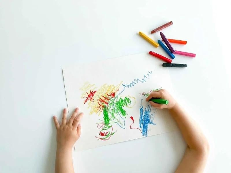 A child is drawing a picture of a tree with crayons.