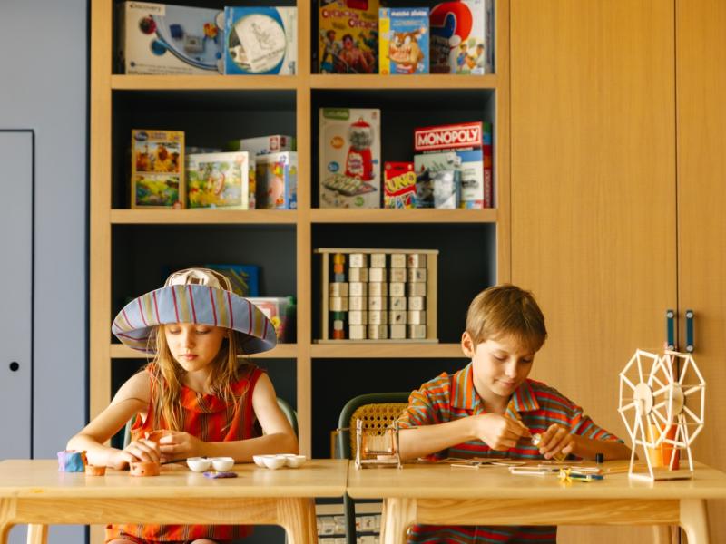 Two children sit and colour at the Kids' Club.