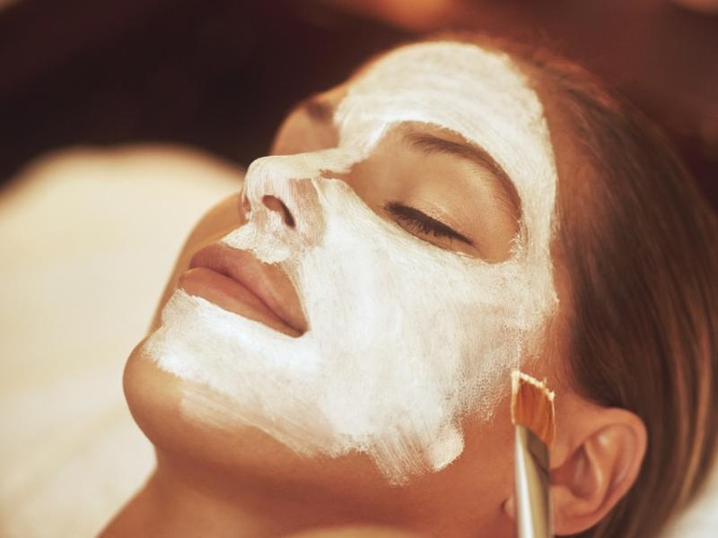 Gros plan sur le visage d'une femme, sur lequel un masque blanc est appliqué au pinceau.